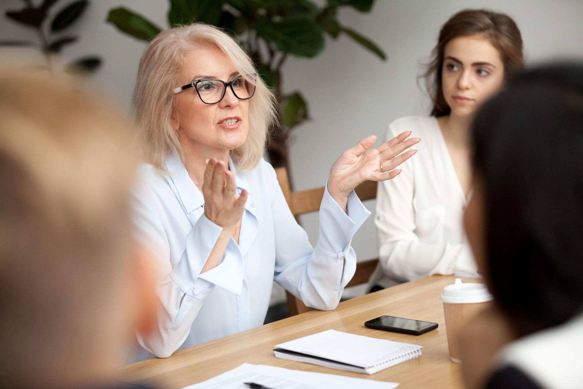 Aged businesswoman, teacher or business coach speaking to young people